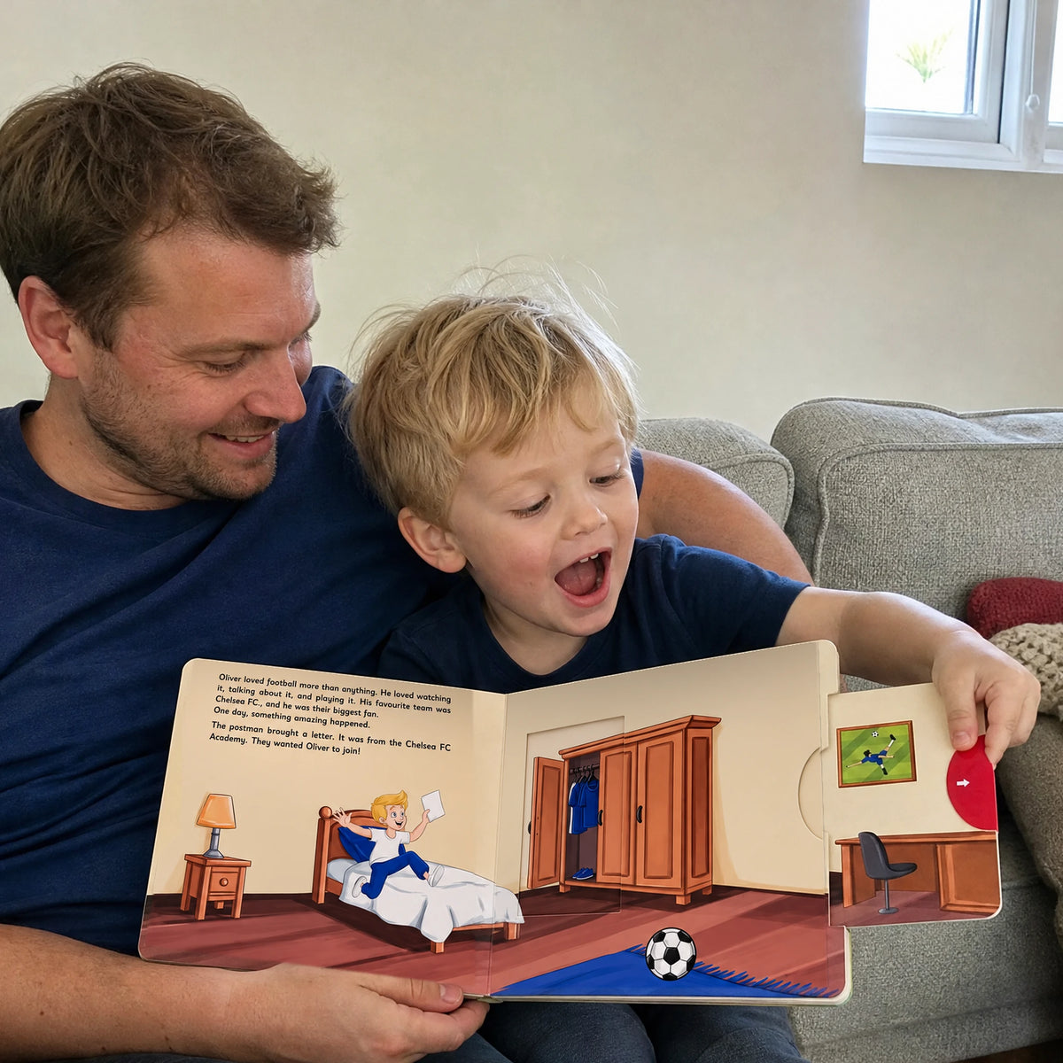Ein Vater und sein kleiner Sohn auf dem Sofa, der Junge zieht an der roten Lasche des Chelsea-Schiebebuchs