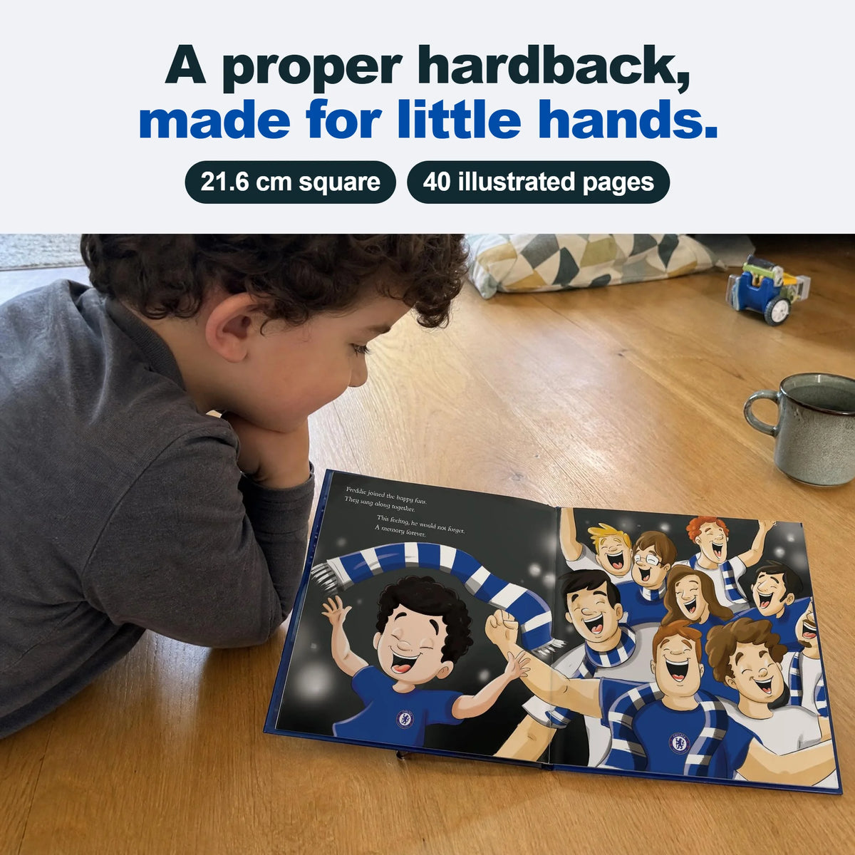 Un bambino sdraiato per terra legge il suo Libro Personalizzato del Chelsea, aperto su una pagina interna.