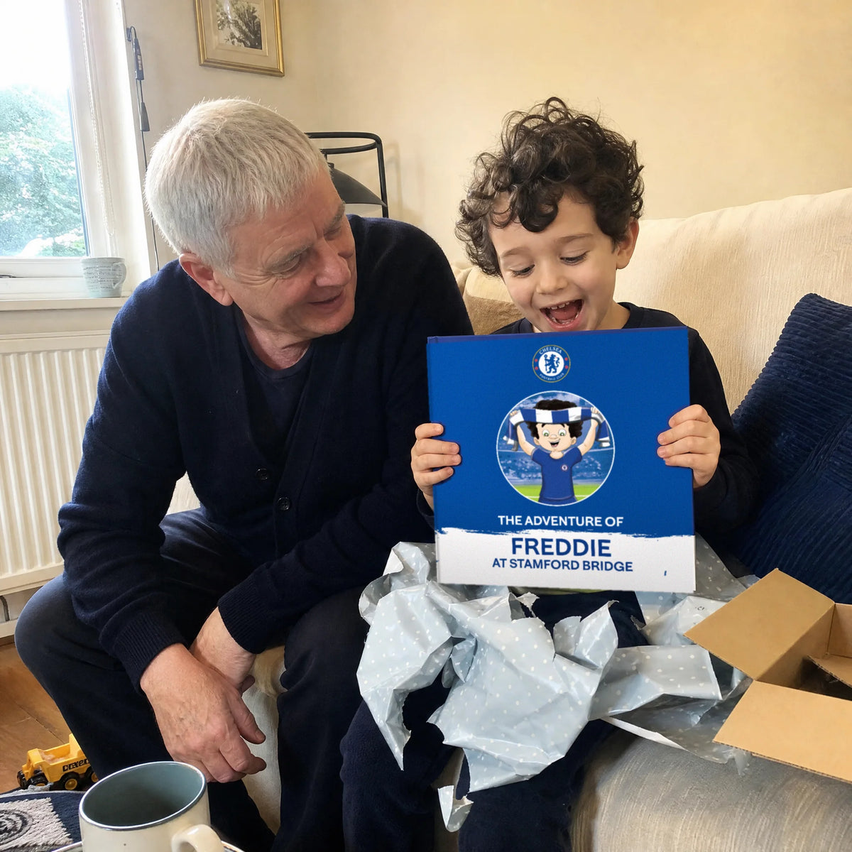 Un nonno e il nipote sul divano, il Libro Personalizzato del Chelsea appena uscito dalla carta da regalo.