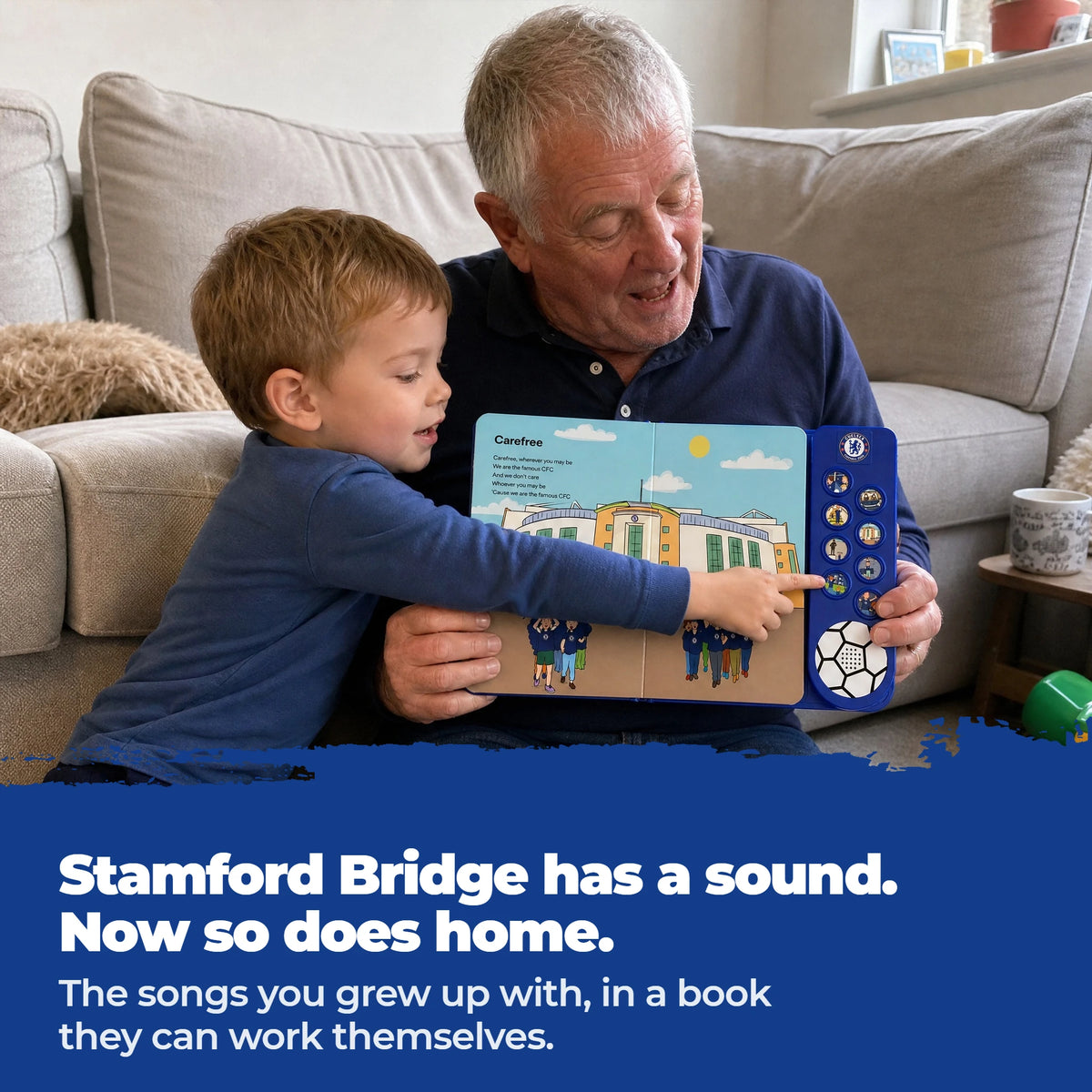 A grandad on the sofa holding the open Chelsea FC Sound Book at chest height while his grandson leans in and presses one of the sound buttons.