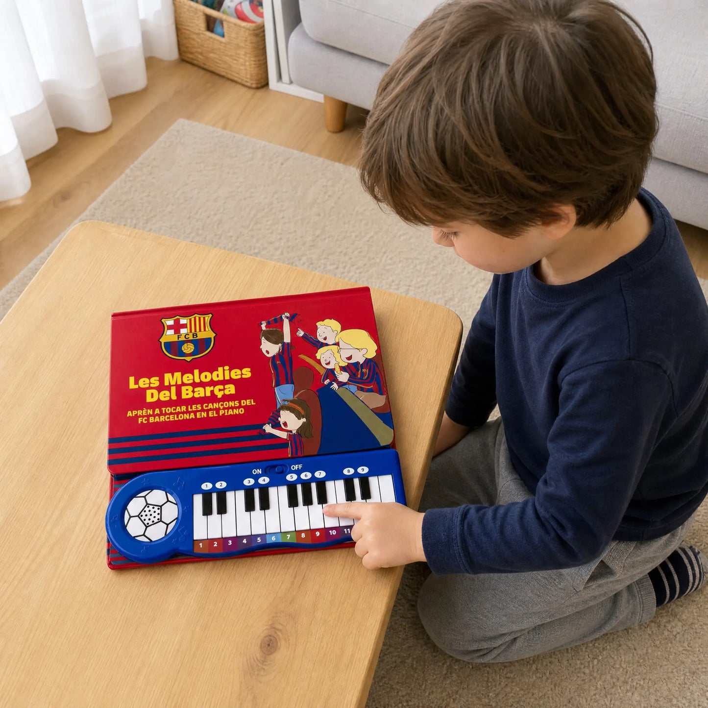 A child kneeling at a low table, playing the keys of the FC Barcelona Piano Book as it lies flat in front of them.