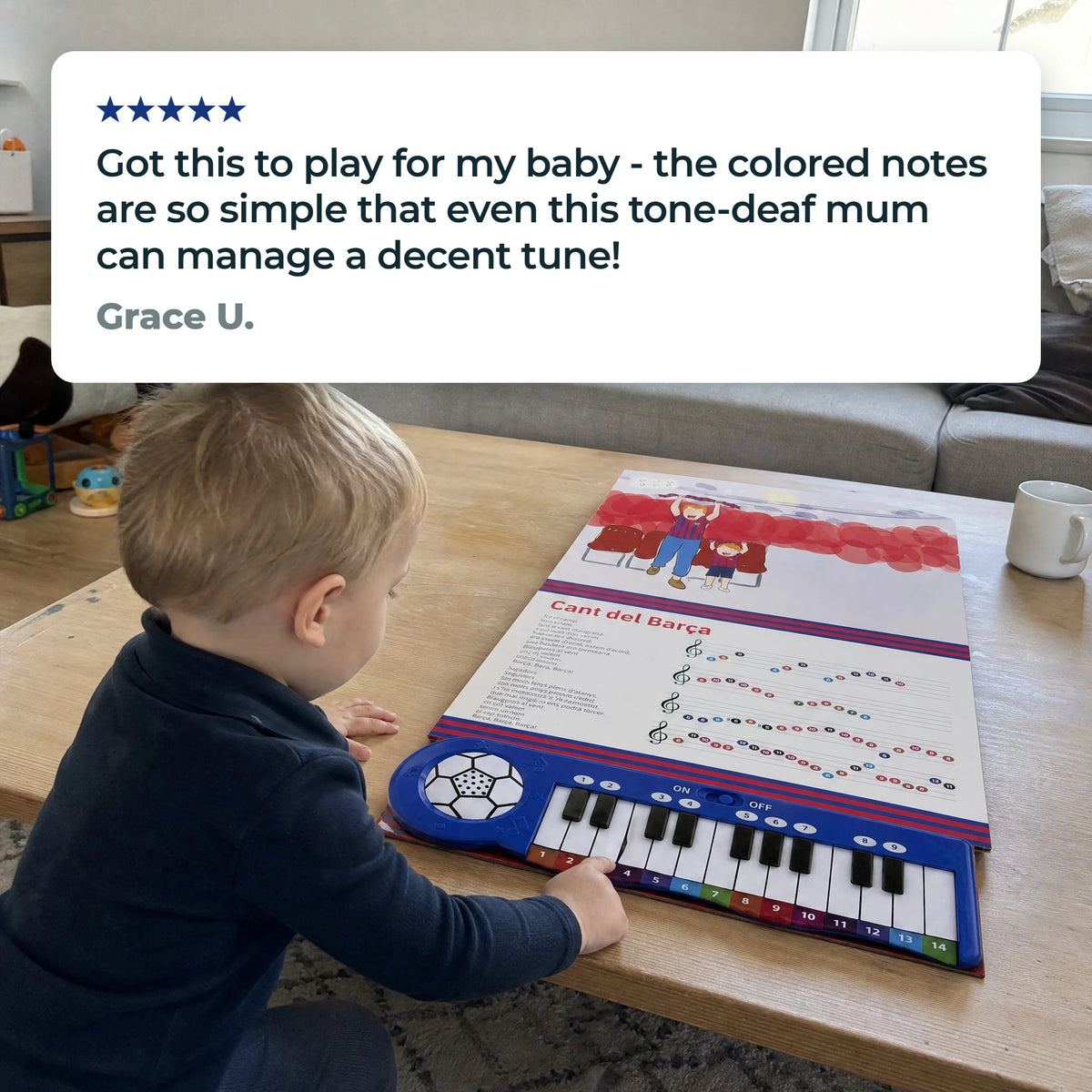 Un bambino piccolo suona i tasti del Libro di Pianoforte del Barça, aperto e steso su un tavolino, sotto una recensione a cinque stelle di Grace U.: «Got this to play for my baby - the colored notes are so simple that even this tone-deaf mum can manage a decent tune!»