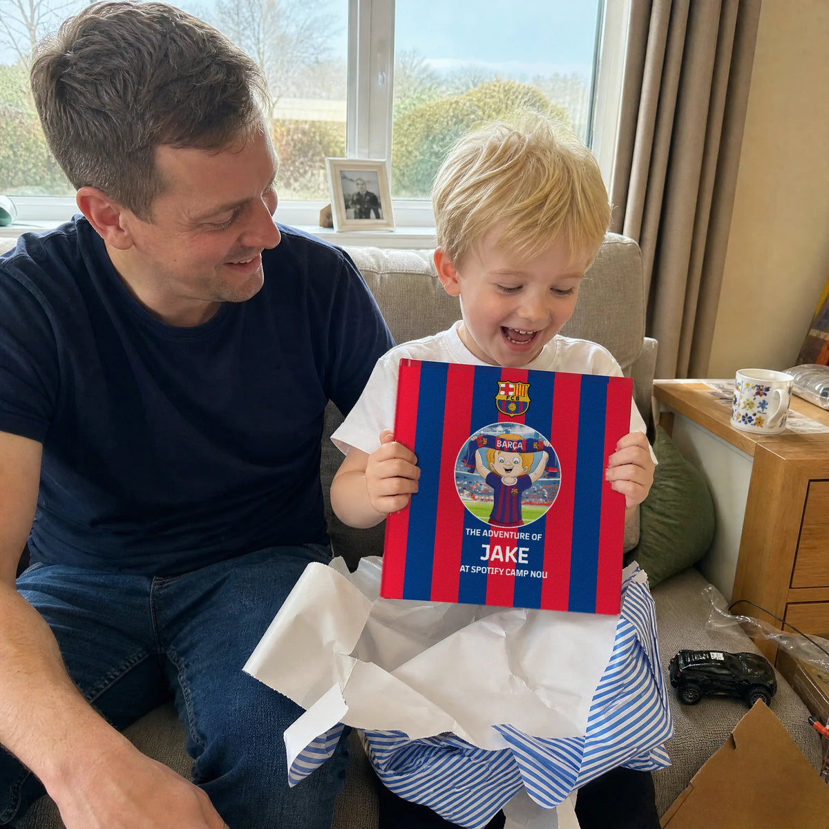 A father and his son on the sofa, the FC Barcelona Personalised Book just out of the wrapping paper.
