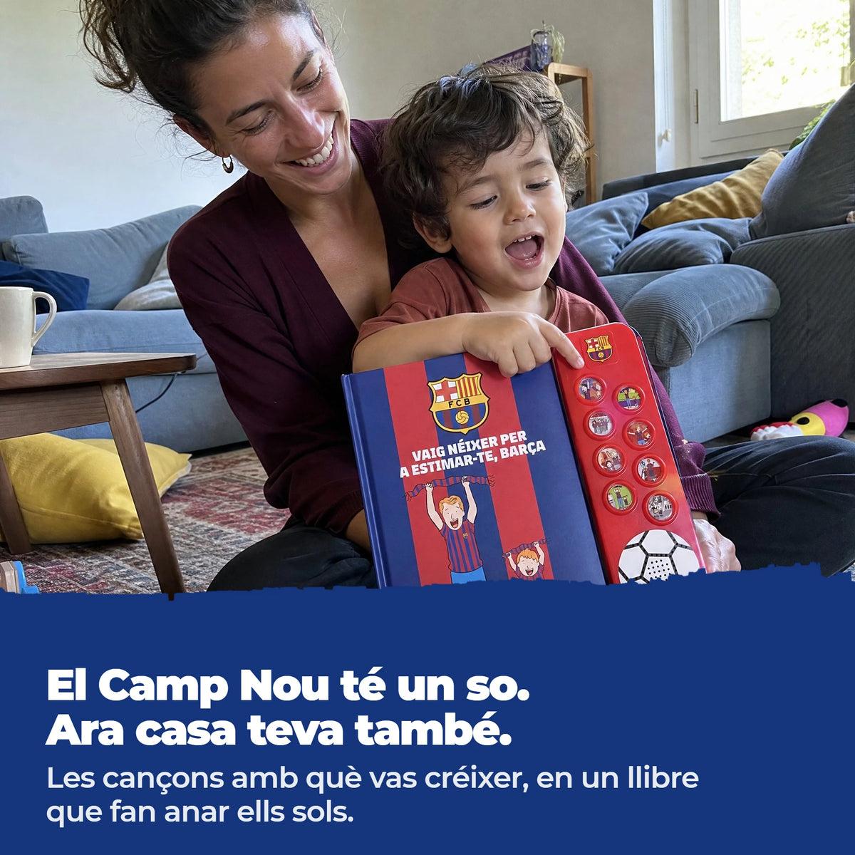 Una mamma e il suo bambino su un tappeto del soggiorno con l'edizione in catalano del libro sonoro dell'FC Barcelona, il bambino preme uno dei pulsanti.