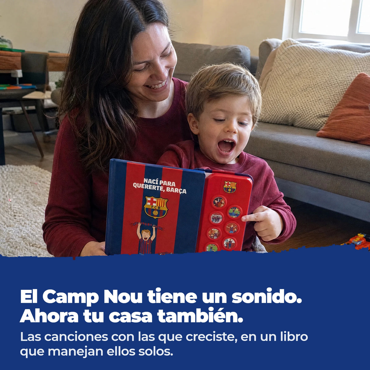 Una mamma e il suo bambino sul divano con l'edizione in spagnolo del libro sonoro dell'FC Barcelona, il bambino preme uno dei pulsanti.