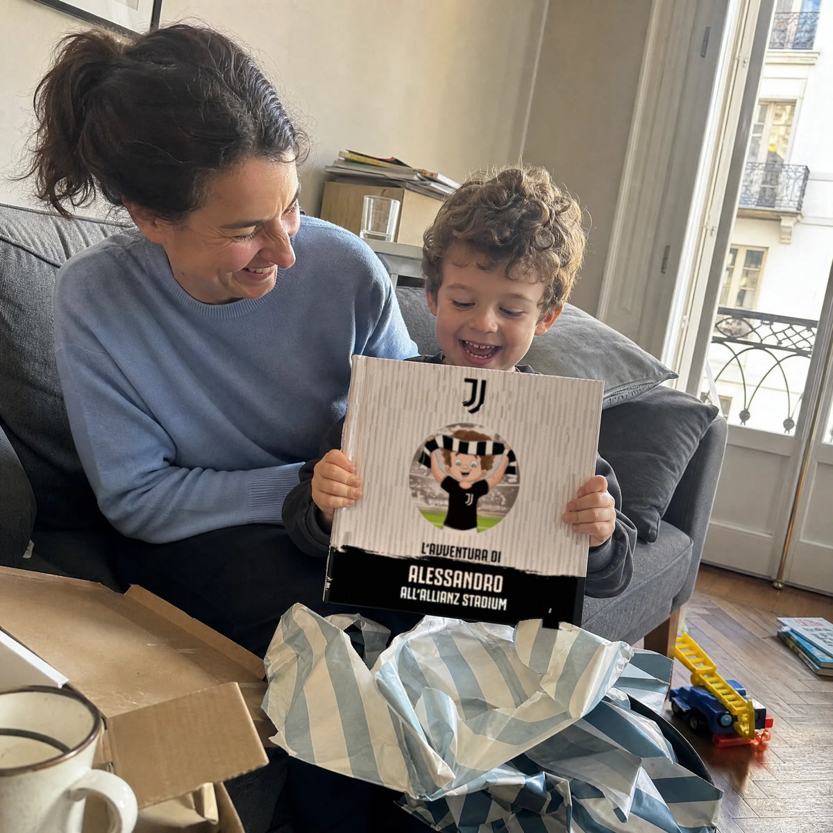 A mother and son on the sofa with the Juventus Personalised Book, just out of the wrapping paper.