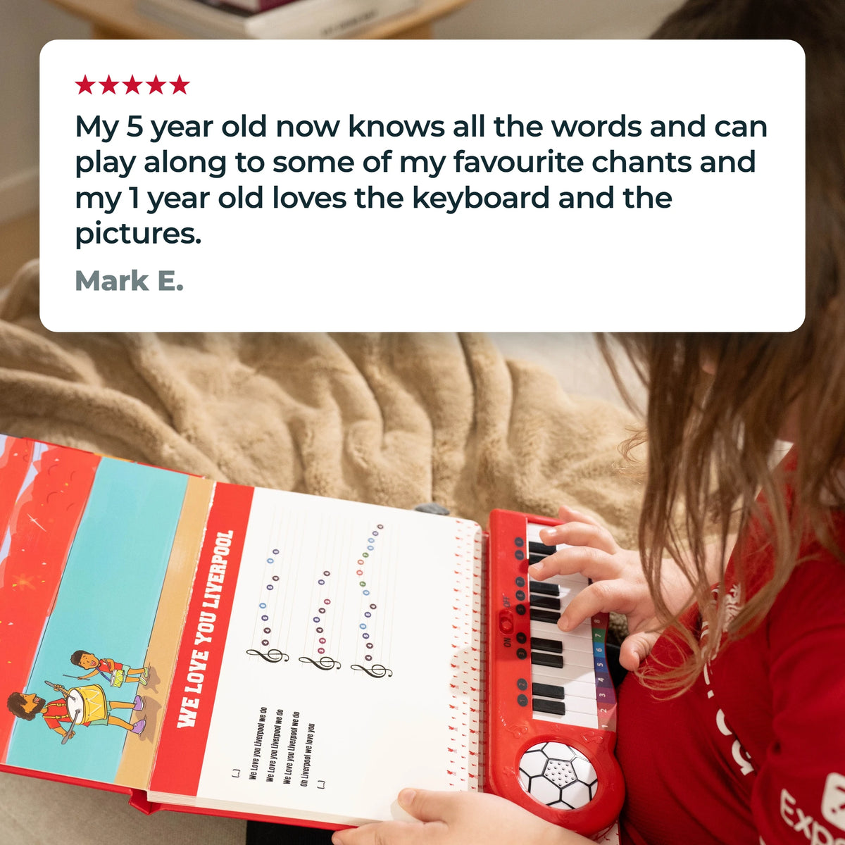 Una bambina con la maglia del Liverpool FC suona i tasti del Libro di Pianoforte sulle ginocchia, sotto una recensione a cinque stelle di Mark E.: «Il mio bambino di 5 anni ora conosce tutte le parole e sa suonare alcuni dei miei cori preferiti, e quello di 1 anno adora la tastiera e le figure.»
