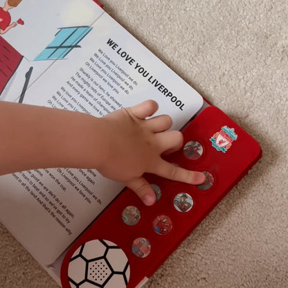 A toddler pressing one of the eight sound buttons on the Liverpool FC Sound Book at home.