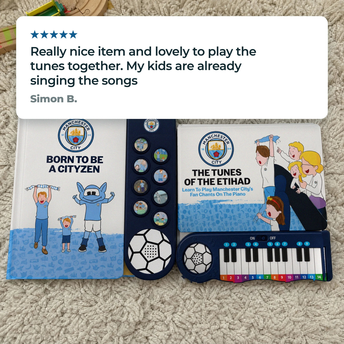Il libro sonoro e il Libro di Pianoforte del Manchester City insieme su un tappeto di casa, con una recensione a cinque stelle di un cliente.