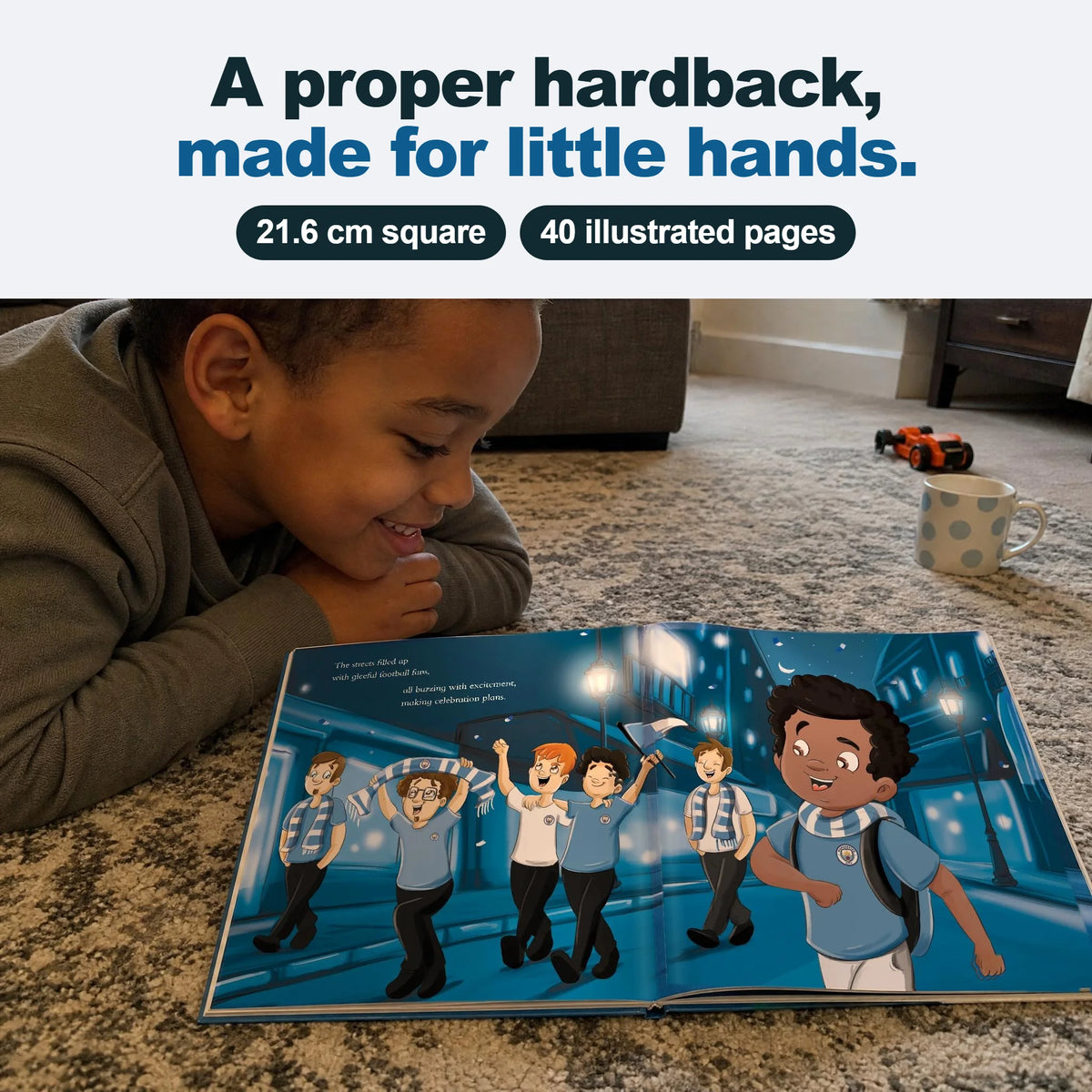 A boy lying on the floor reading his Manchester City Personalised Book, open on an inside spread.
