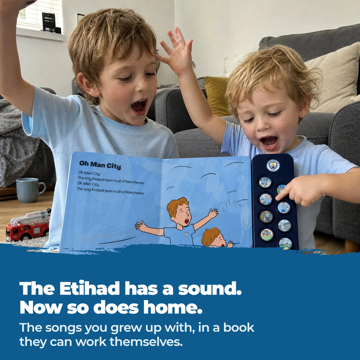 Two young children in plain sky-blue tops holding the open Manchester City Sound Book up between them, mid-chant, the younger one's finger on a sound button.