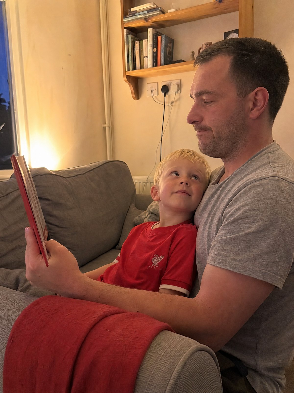A dad reading the book to his son in his lap, stopping mid-page
