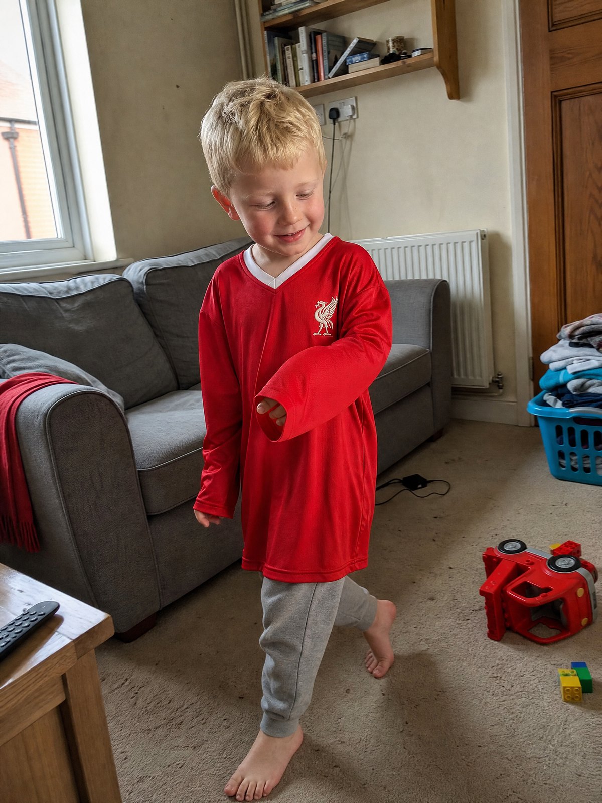 A four-year-old boy in a Liverpool shirt a size too big, walking across the front room