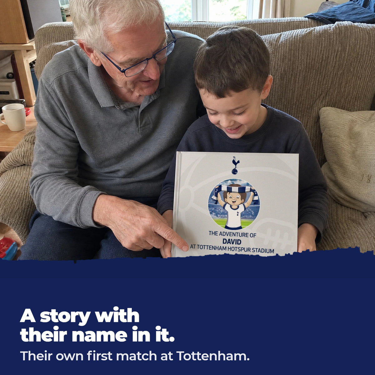 A grandad and his grandson on the sofa, the grandad pointing at the child's name printed on the cover of the Spurs Personalised Book.