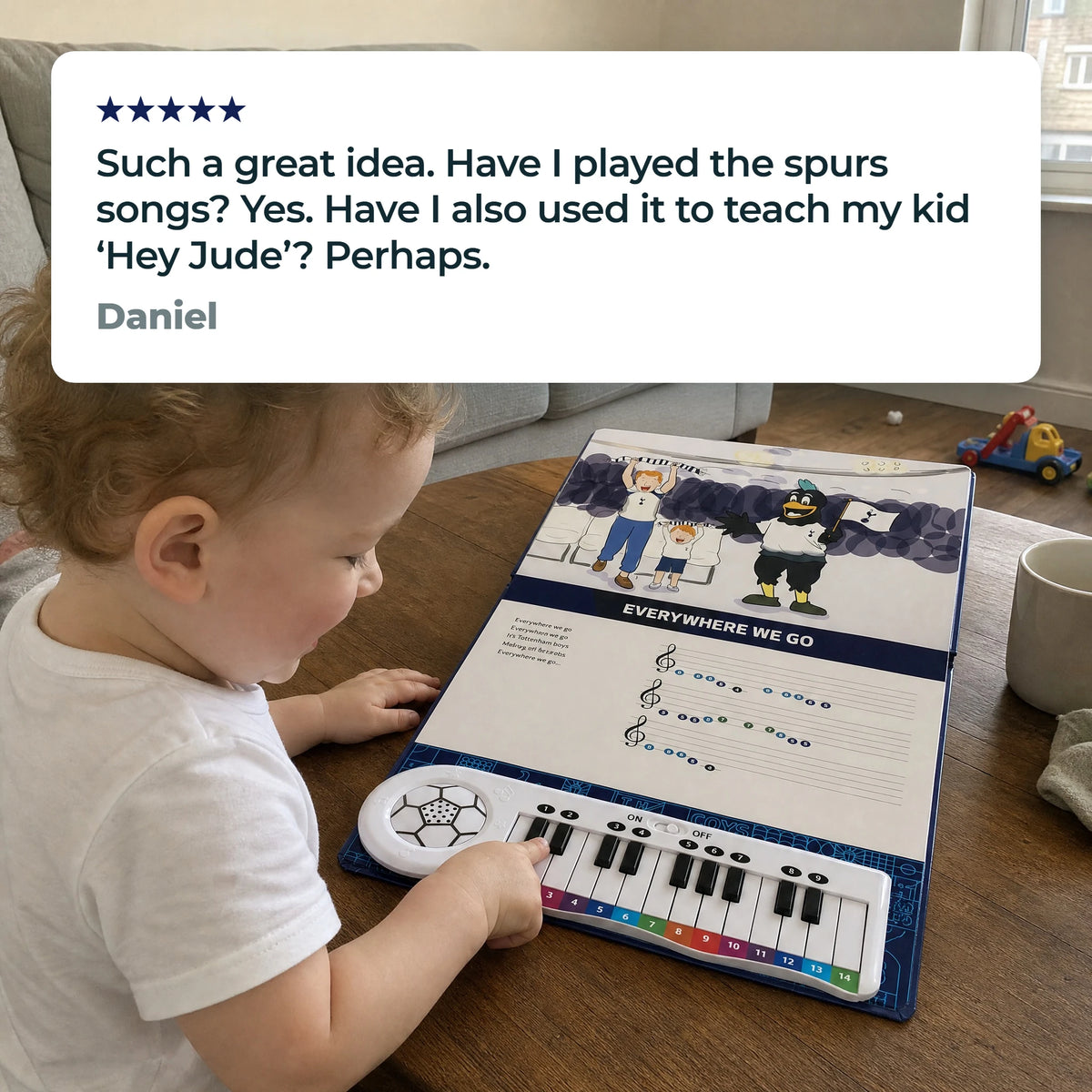 Un bambino piccolo suona i tasti del Libro di Pianoforte del Tottenham, aperto e steso su un tavolino, sotto una recensione a cinque stelle di Daniel: «Such a great idea. Have I played the spurs songs? Yes. Have I also used it to teach my kid ‘Hey Jude’? Perhaps.»