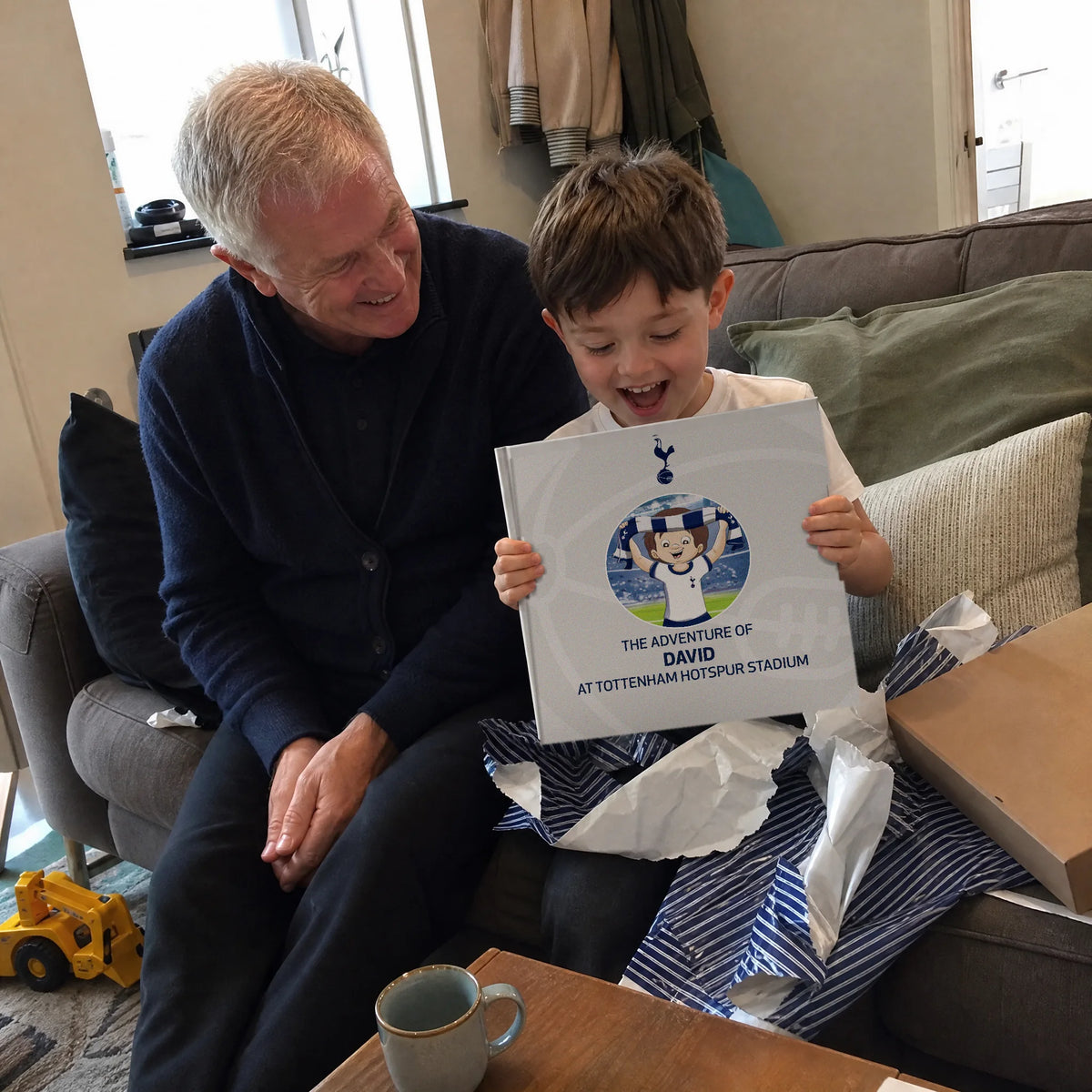 Un nonno e il nipote sul divano, il Libro Personalizzato del Tottenham Hotspur appena uscito dalla carta da regalo.