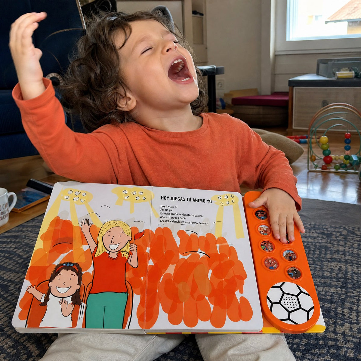 Un niño pequeño canta a pleno pulmón con el Libro Musical del Valencia CF abierto en el regazo, una mano sobre los botones y la otra en alto.