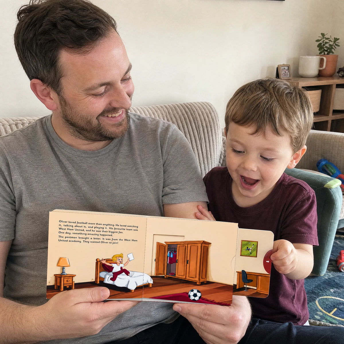 Ein Vater und sein kleiner Sohn auf dem Sofa, der Junge zieht an der roten Lasche des West-Ham-Schiebebuchs