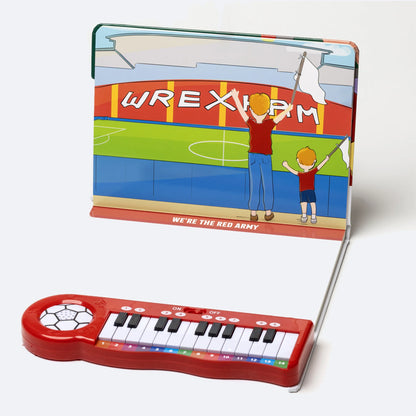 The Piano Book open, showing an illustrated spread with colour-coded sheet music above the keyboard.